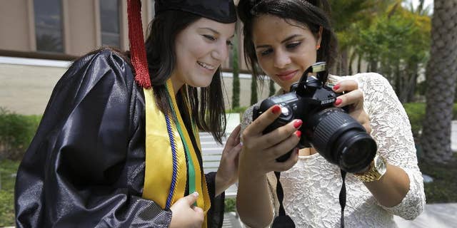 April 29, 2014: University of South Florida graduating seniors Kyra Ciotti, 22, of Tampa, Fla., left, and Rita Sibaja, 24, of Winter Haven, Fla., look at photos that Rita took of Kyra in her cap and gown Tuesday, April 29, 2014, in Tampa, Fla. The university has banned all self portraits, also known as "selfies," during their 2014 graduation exercises. (AP/Chris O'Meara)