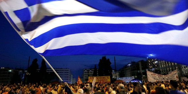 A demonstrator waves a Greek flag during an anti-austerity rally in central Athens, Friday, July 10, 2015. Greek Prime Minister Alexis Tsipras sought his left-wing party's backing on Friday for a new budget austerity package that is harsher than what he urged Greeks to reject in a vote just last week, but would provide the country will longer-term financial support. (AP Photo/Petros Karadjias)