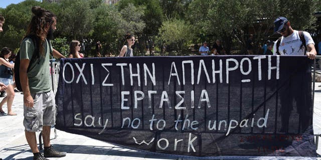 Short-term contract employees of the Culture Ministry, unpaid for over six months, protest outside the entrance of the ancient Acropolis hill in Athens, Thursday, July 23, 2015. Greece's radical left-led government survived another revolt by rebels in the early hours of Thursday, passing reforms that should pave the way for the imminent start of bailout discussions with European creditors. Sign says in Greek and English "Say no to the unpaid work." (AP Photo/Giannis Papanikos)