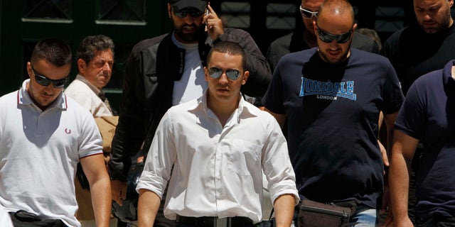 June 11, 2012: The spokesman of Greece's extreme-right Golden Dawn party Ilias Kasidiaris, center, is escorted by party members as they exit the prosecutor's office in Athens.