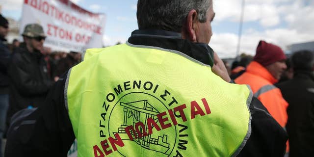 A dock worker with a "Not for sale" sign on his vest takes part in a protest against government plans to further privatize the harbor of Piraeus, Greece's busiest, in Piraeus, on Tuesday, March 11, 2014. Several hundred people took part in the peaceful demonstration. Once a separate town, Piraeus is now incorporated in the greater Athens area. (AP Photo/Petros Giannakouris)