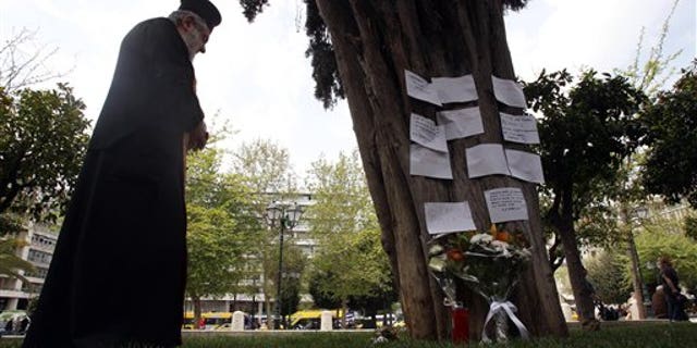 April 4, 2012: A Greek Orthodox priest holds a memorial service, at the site where an elderly man fatally shot himself at Athens' main Syntagma square.