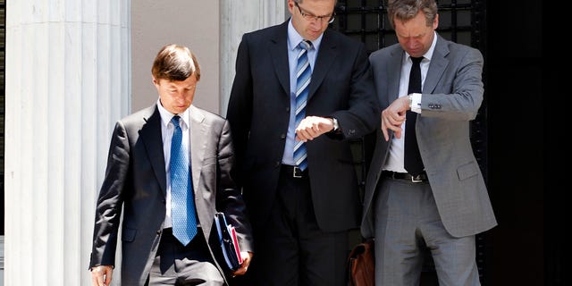 Poul Thomsen, the International Monetary Fund mission chief in Greece, right, and Klaus Masuch of the European Central Bank, center, check their watches next to European Commission official Matthias Mors as they leave Maximou mansion after a meeting with Greek Prime Minster Antonis Samaras, in Athens, Thursday, July 5, 2012. The debt inspectors from the European Central Bank, European Commission and International Monetary Fund, known as the troika, were meeting the new government, whose coalition partners want to persuade the country's rescue creditors to ease some of the strict terms of its bailout. (AP Photo/Petros Giannakouris)