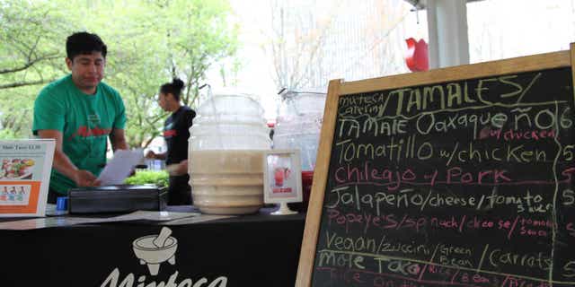 HOLD FOR MOVEMENT THURSDAY MAY 1 - In this photo Tuesday, April 15, 2014 photo, Gaudencio Felipe Asuncion prepares a traditional Oaxacan dish of tamales with mole sauce at the Lloyd Farmers Market in Portland, Oregon. The young man's mother, Paula Asuncion, started the food catering service after being part of a Portland micro-business development program for Spanish speakers run by Hacienda CDC. (AP Photo/Gosia Wozniacka)