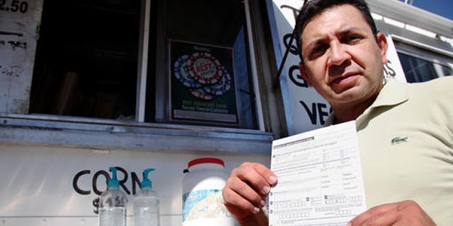 Carlos Zamora shows a voter registration card from a pile placed on the counter of the Tierra Caliente taco truck on Thursday, Sept. 29, 2016, in Houston. Zamora is with Mi Familia Vota, a Latino activist group that seeks to register more voters in the Latino community. Mi Familia Vota partnered with a local design firm to make eight of the city's taco trucks into mobile voter registration booths after a surrogate of Republican presidential candidate Donald Trump recently suggested that unless the United States fortifies its borders and tightens immigration limits, "You're going to have taco trucks on every corner." (AP Photo/John L. Mone)