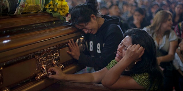 Two unidentified relatives weep in front of the coffin of a person that died during a bus crash a day earlier during a mass at the church in the town of San Martin Jilotepeque, Guatemala, Tuesday, Sept.10, 2013. The death toll in a rural Guatemala bus crash rose to 46 on Tuesday, after two more people died of injuries suffered in the vehicle's plunge into a deep canyon. (AP Photo / Luis Soto)