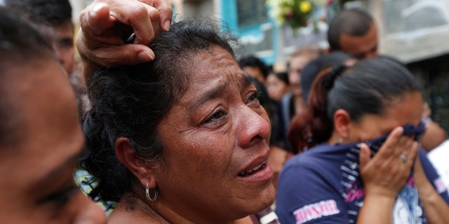Relatives weep during the burial of Amilcar Estrada and his 10-year-old niece Maria Jose, who died in a mudslide, in the Santa Catarina Pinula cemetery on the outskirts of Guatemala City, Sunday, Oct. 4, 2015. Rescue workers recovered more bodies Saturday after a hillside collapsed on homes late Thursday, while more are feared still buried in the rubble. (AP Photo/Moises Castillo)