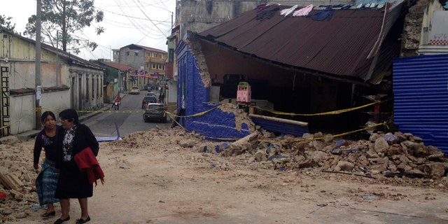 Nov. 7, 2012: Two women walk past a building damaged after a magnitude 7.4 earthquake struck in San Marcos, Guatemala.