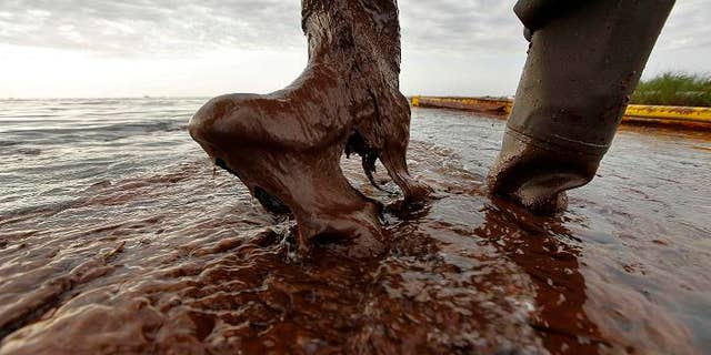 June 5: In this file photo, Plaquemines Parish coastal zone director P.J. Hahn lifts his boot out of thick beached oil at Queen Bess Island in Barataria Bay, just off the Gulf of Mexico in Plaquemines Parish, La.