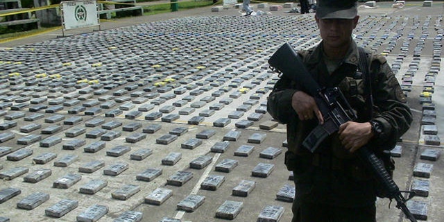 Anti-narcotics police officer guards packages of cocaine, totaling 2.9 tons, seized during a raid at a lab in the rural area of Necocli, in the norther Colombian Caribe coast, Colombia on Monday, June 26, 2006.. (AP Photo/Luis Benavides)