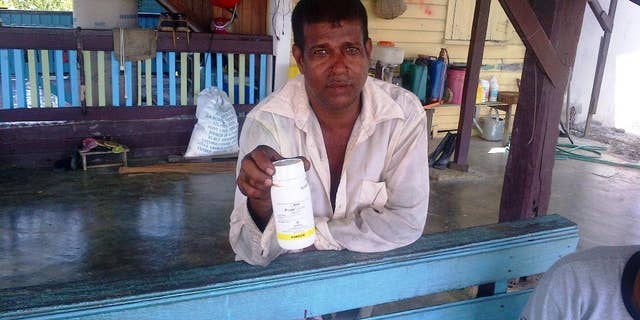 In this Monday, Oct. 6, 2014 photo, Vijai Ramlackhan holds a container of pesticide similar to the type his 17-year-old son used to commit suicide on their farm in the Berbice region of Guyana, a country that the World Health Organization says has the highest rate of suicide in the world. (AP Photo/Bert Wilkinson)