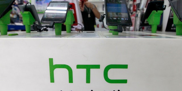 Customers look at HTC smartphones in a mobile phone shop in Taipei July 30, 2013. Taiwan's HTC Corp expects revenue to fall as much as 30 percent in the third quarter compared to the previous three months, far below analysts' forecasts. REUTERS/Pichi Chuang (TAIWAN - Tags: BUSINESS TELECOMS) - RTX124KL
