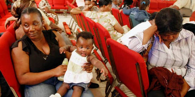 FILE - In this Thursday, Jan. 21, 2010, file photo, Haitian national Carole Manigat, left, holds her daughter Hadassa Carole Albert as she waits for her turn to fill out temporary protective status papers at Notre Dame d'Haiti Catholic Church in the Little Haiti neighborhood in Miami. The U.S. Department of Homeland Security said Thursday, Sept. 22, 2016, that it was widening efforts to deport Haitians, a response to thousands of immigrants from the Caribbean nation who have overwhelmed California border crossings with Mexico in recent months. The move lifts special protections that shielded Haitians from deportation after their nationâs 2010 earthquake. (AP Photo/Alan Diaz, File)