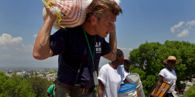 In this Saturday, April 10, 2010 file photo, U.S. actor Sean Penn carries the belongings of a person displaced by the earthquake as people are relocated from the Petionville Golf Club to a new camp, Corail-Cesselesse, in Port-au-Prince, Haiti. (AP Photo/Ramon Espinosa)