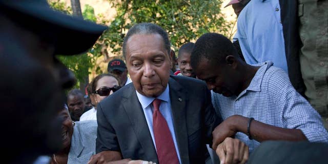 FILE - In this Feb. 8, 2011 file photo, former Haitian dictator Jean-Claude "Baby Doc" Duvalier's supporters help him negotiate an uneven path during a visit to his mother's hometown and grave site in Leogane, Haiti. Duvalier, the self-designated "president-for-life" who died Oct. 4, 2014, from an apparent heart attack, will not get a formal state funeral, but have a "simple, private,"funeral arranged by friends and family in Haiti, attorney Reynolds Georges said in an interview. (AP Photo/Ramon Espinosa, File)