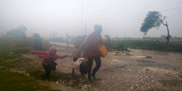 Residents head to a shelter in Leogane, Haiti, Tuesday, Oct. 4, 2016. Matthew slammed into Haiti's southwestern tip with howling, 145 mph winds Tuesday, tearing off roofs in the poor and largely rural area, uprooting trees and leaving rivers bloated and choked with debris. (AP Photo/Dieu Nalio Chery)