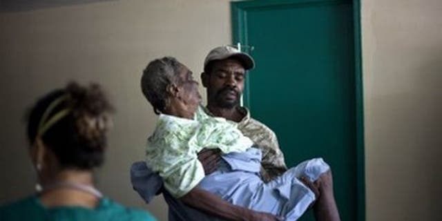 In this photo from Nov. 8, 2010, a woman suffering from cholera symptoms is carried by a volunteer at the hospital in Archaie, Haiti. (AP Photo)