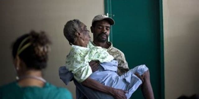 In this photo from Nov. 8, 2010, a woman suffering from cholera symptoms is carried by a volunteer at the hospital in Archaie, Haiti. (AP Photo)