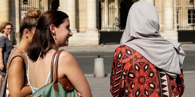 A woman wearing a Muslim headscarf, right, and who refused to be identified, stands outside the Conseil d'Etat, France's top administrative court, in Paris, Friday, Aug. 26, 2016. The court has overturned a town burkini ban amid shock and anger worldwide after some Muslim women were ordered to remove body-concealing garments on French Riviera beaches. (AP Photo/Thomas Padilla)