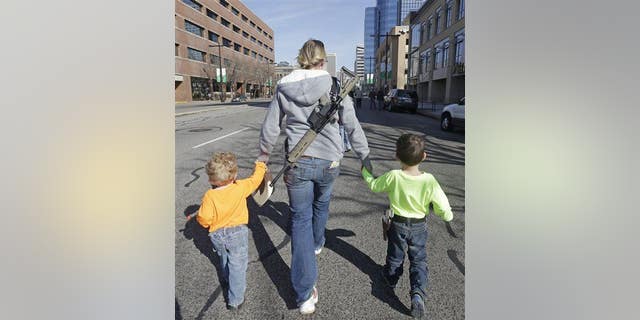 Gun rights activist Siri Davidson, center, has her AR15 slung on her back, as she walks with her children Keaton, 2, and Porter, 5, during a march for the 2nd Amendment rights Saturday, March 2, 2013, in Salt Lake City.