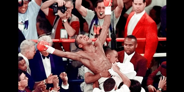 FILE - In this Sept. 18, 1999 file photo, Felix Trinidad is held up by his corner in after defeating Oscar De La Hoya by way of decision after 12 rounds, to win the WBC/IBF Welterweight Championship at the Mandalay Bay Events Center in Las Vegas. De La Hoya, Trinidad and Joe Calzaghe head the class of 2014 to be inducted into the International Boxing Hall of Fame. (AP Photo/Laura Rauch, File)