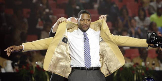 Michael Strahan has his gold jacket put on by his presenter Jay Glazer Friday, Aug. 1, 2014 during the Pro Football Hall of Fame Enshrinees' Dinner in Canton, Ohio. The induction ceremony will take place Saturday in Canton's Fawcett Stadium (AP Photo / The Repository, Bob Rossiter)