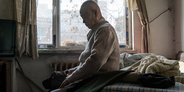 TIANJIN, CHINA - JANUARY 19: Han Zicheng, 85, sits in bed to take off his pants, revealing the wool pants inside that he usually wears at home. (Photo by Yan Cong for The Washington Post via Getty Images)
