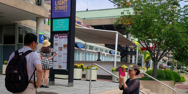 May 27, 2015: Tourists pause along the waterfront by Harborplace, Baltimore, Md.