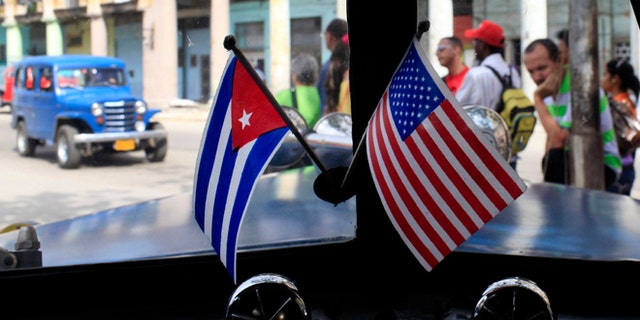 FILE - In this March 22, 2013 file photo, miniature flags representing Cuba and the U.S. are displayed on the dash of an American classic car in Havana, Cuba. Everyone warns you Old Havana is a facade, but it's impossible not to be taken by its charms. For a foreigner who isn't coming with predetermined notions of Cuba as global boogeyman or socialist paradise, each alley and avenue, each conversation with a Cuban, complicates the picture. (AP Photo/Franklin Reyes, File)