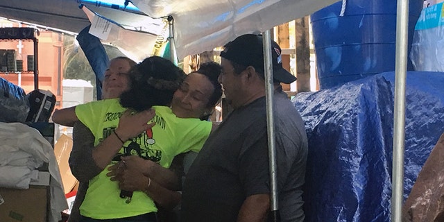 Keala Martins-Keliihoomalu, a 27-year-old full-time student at the University of Hawaii at Hilo who helped organize the Pu’uhonua o Puna community donation center, hugs two people who came to the center.