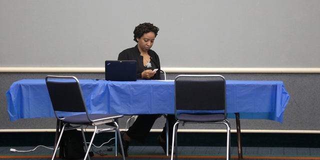 Health care assister Charolyn Mosley looks at her cell phone as she waits to help anyone looking to shop the federal marketplace for health insurance at a convention center in Texas City, Texas, Saturday, March 1, 2014. Though organizers had recruited assisters to handle as many as 400 people in navigating the federal insurance marketplace, only a handful had come by in the first hours of operations.