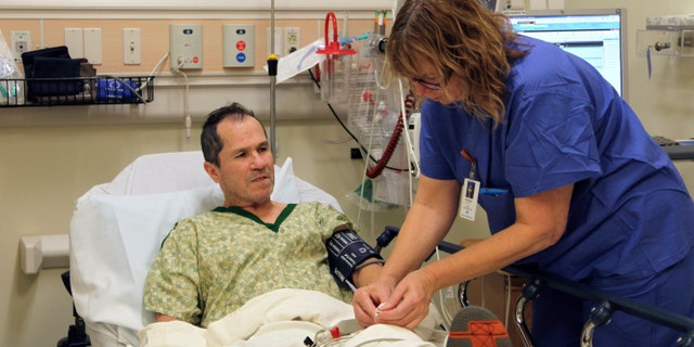 In this Wednesday, Dec. 3, 2014 photo, a nurse prepares liver cancer patient Crispin Lopez Serrano for an endoscopy at a Clackamas, Ore. hospital. Lopez Serrano, a Mexican native who is fully bilingual, says his care improved after he received culturally relevant palliative care from a Portland nonprofit organization, helping him to retain his doctors, boost his health literacy, and receive emotional support. (AP Photo/Gosia Wozniacka)