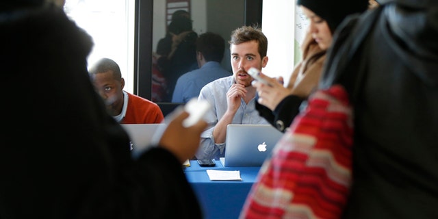 David Bransfield, a state outreach coordinator for Young Invincibles, a group which supports President Barack Obama's health care law, right, is seated with Dr. Christopher Riley, left, of Assist DC, as they look to sign up students for health care at the University of the District of Columbia in Washington, Thursday, Jan. 30, 2014. An army of workers and volunteers has fanned out around the country trying to enroll young and healthy people in health insurance now available through Obamaâs signature law. (AP Photo/Charles Dharapak)