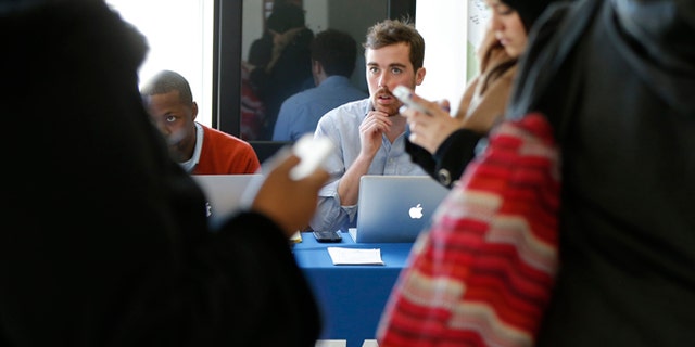 David Bransfield, a state outreach coordinator for Young Invincibles, a group which supports President Barack Obama's health care law, right, is seated with Dr. Christopher Riley, left, of Assist DC, as they look to sign up students for health care at the University of the District of Columbia in Washington, Thursday, Jan. 30, 2014. An army of workers and volunteers has fanned out around the country trying to enroll young and healthy people in health insurance now available through Obamaâs signature law. (AP Photo/Charles Dharapak)