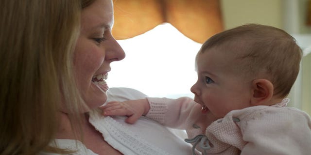 In this photo taken Sept. 24, 2013, Holly Sloan interacts with her baby Amelia at their home in Warrenton, Va. Ameliaâs family enrolled in a study that is deciding the DNA of babies, as researchers explore whether gene-mapping one day should become a part of newborn care.