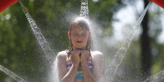 In a July 20, 2011 photo, Mckenna Dorvinen, 11, of Kingsley, Mich., finds relief from Wednesday's heat on the splash pad in Brownson Memorial Park. Much of the nation is doing what it can to adapt to the oppressive summer heat that has settled in.