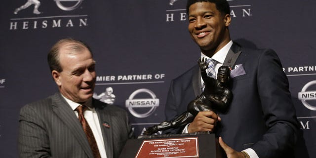 December 14, 2013: Florida State quarterback Jameis Winston, right, stands with FSU coach Jimbo Fisher while holding the Heisman Trophy after winning the award in New York. (AP Photo/Julio Cortez)