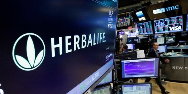 FILE - In this May 6, 2016 file photo, the Herbalife logo appears above the post where it trades on the floor of the New York Stock Exchange. The Federal Trade Commission is closing an investigation of Herbalife and the multinational, nutritional supplements company will to pay $200 million to settlement allegations that it deceived consumers. The company said in a written statement on Friday, July 15, that the FTC settlement doesnââ¬â¢t change its business model as a direct selling company. (AP Photo/Richard Drew)
