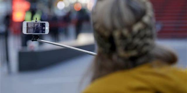 Sandy Johal uses a selfie stick to take a picture of herself in Times Square in New York, Jan. 8, 2015.