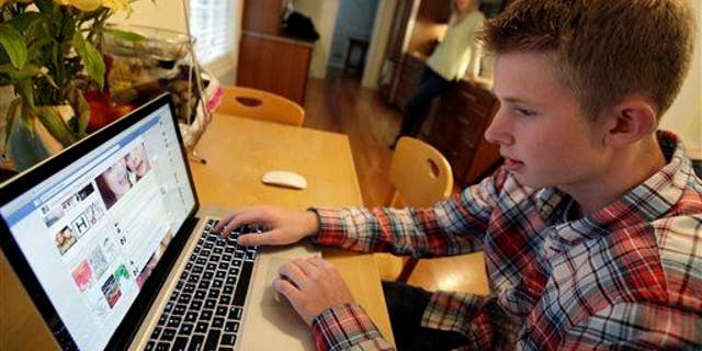 A young teenager checks his Facebook page in this image.