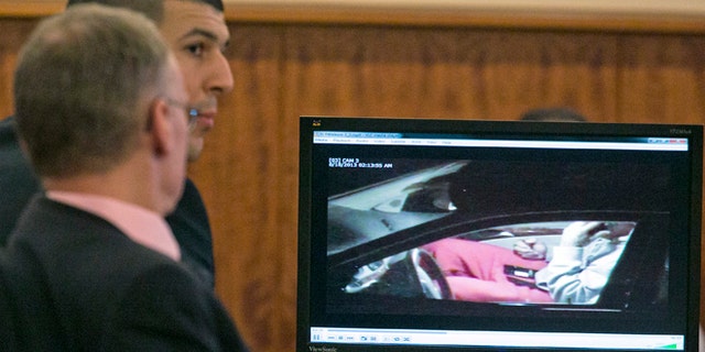 Aaron Hernandez, rear, and his attorney Charles Rankin watch surveillance video of Hernandez handling cell phones during his murder trial at the Bristol County Superior Court in Fall River, Mass. on Tuesday, Feb. 17, 2015. Hernandez is accused in the June 17, 2013, killing of Odin Lloyd, who was dating his fiancée's sister. (AP Photo/Dominick Reuter, Pool)