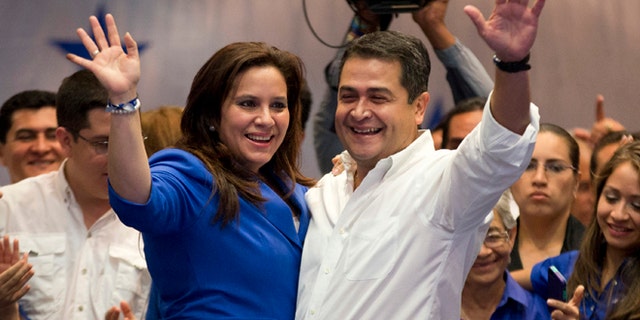 National Party presidential candidate Juan Orlando Hernandez and his wife, Ana Garcia, left, waves to supporters during his victory speech, after partial election results in Tegucigalpa, Honduras, Sunday, Nov. 24, 2013. The electoral court said preliminary results gave Hernandez a comfortable edge over Xiomara Castro, whose husband Manuel Zelaya was overthrown in the military-backed coup.(AP Photo/Eduardo Verdugo)