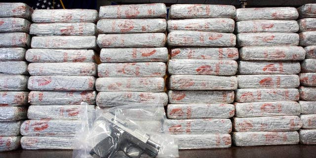 A firearm and 154 pounds of heroin worth at least $50 million on display at a Drug Enforcement Administration news conference in May 2015.