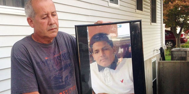 Abraham Chaparro holds a photograph of his murdered stepson Miguel Garcia-Moran, outside his home in Brentwood, N.Y.