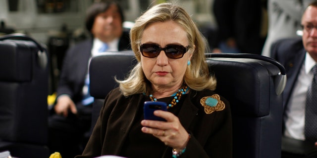 In this Oct. 18, 2011, file photo, then-Secretary of State Hillary Rodham Clinton works from a desk inside a C-17 military plane upon her departure from Malta, in the Mediterranean Sea, bound for Tripoli, Libya.