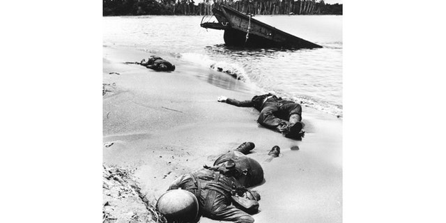 Three dead Americans lie on the beach at Buna.