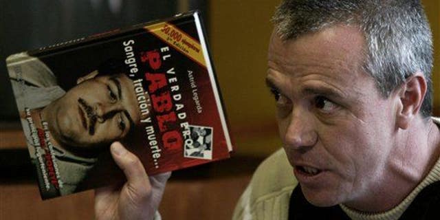 In this June 27, 2006, photo, Jhon Jairo Velasquez, a former hit man for Pablo Escobar, testifies while holding a book titled "The True Pablo: Blood, Treason, and Death."