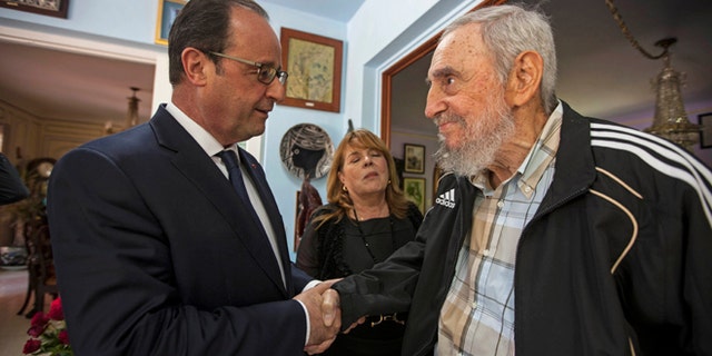 Cuba's former leader Fidel Castro, right, shakes hands with French President Francois Hollande in Havana, Cuba, Monday, May 11, 2015. The woman between the two men is a translator. Hollande is the first French leader to visit the island nation in more than a century and also the first Western leader to travel to Cuba since the surprise announcement in December of a rapprochement between Washington and Havana. (AP Photo/Alex Castro)
