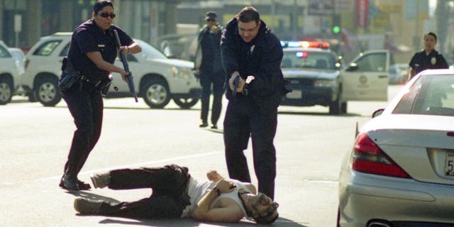 December 9, 2011: This image provided by Gregory Bojorquez shows Los Angeles Police officers advancing on a wounded gunman at sunset and Vine streets in Los Angeles.