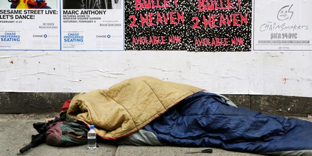 A homeless person sleeps on a sidewalk, Monday, Dec. 21, 2015 in New York. Homeless advocacy groups are threatening legal action against the city over its plans to conduct an aggressive homeless outreach program. The groups say they fear police involvement in the campaign will result in more arrests of homeless people. (AP Photo/Mark Lennihan)